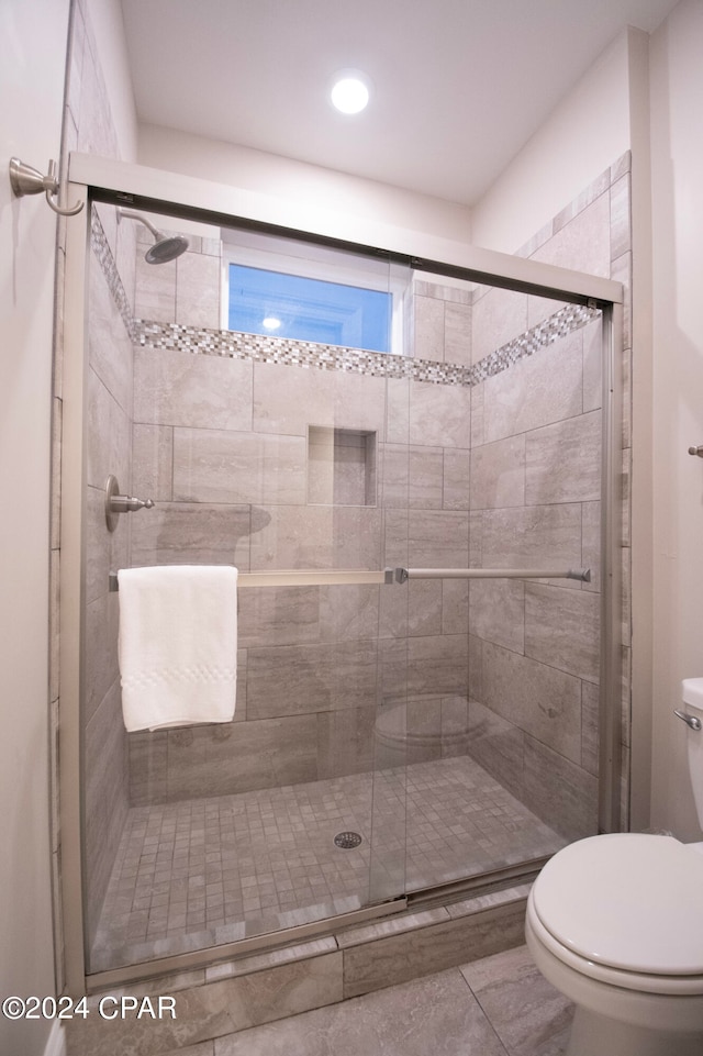 bathroom with an enclosed shower, tile floors, and toilet