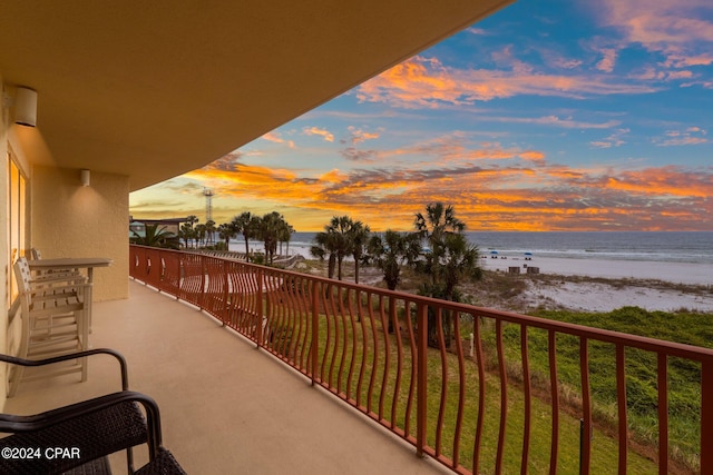 balcony at dusk featuring a water view