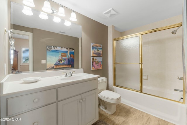 full bathroom with enclosed tub / shower combo, toilet, vanity, and hardwood / wood-style floors