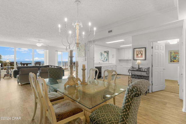 dining area with an inviting chandelier, a textured ceiling, and light wood-type flooring