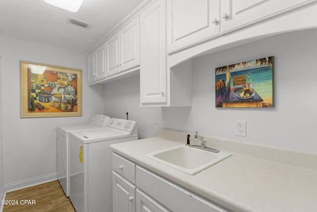 laundry room with sink, wood-type flooring, cabinets, and washing machine and clothes dryer