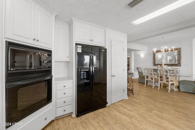 kitchen with a textured ceiling, a notable chandelier, light hardwood / wood-style floors, white cabinetry, and black appliances