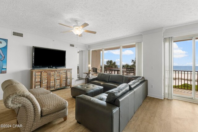 living room featuring hardwood / wood-style floors, plenty of natural light, a water view, and a textured ceiling