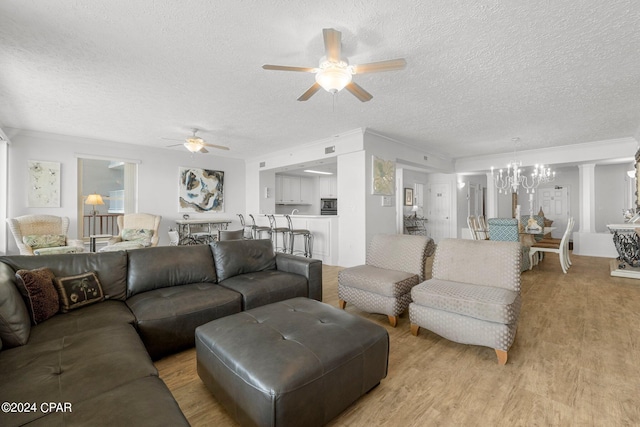 living room featuring ceiling fan with notable chandelier, a textured ceiling, and light wood-type flooring