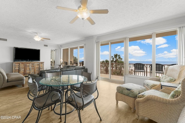 dining space with light hardwood / wood-style flooring, ceiling fan, and a textured ceiling