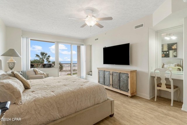 bedroom with access to outside, light hardwood / wood-style floors, ceiling fan, and a textured ceiling