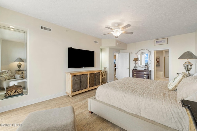 bedroom featuring ensuite bathroom, ceiling fan, a textured ceiling, and light wood-type flooring