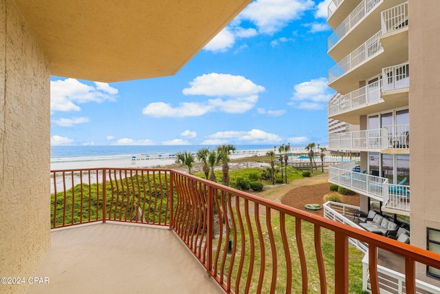 balcony with a water view and a view of the beach