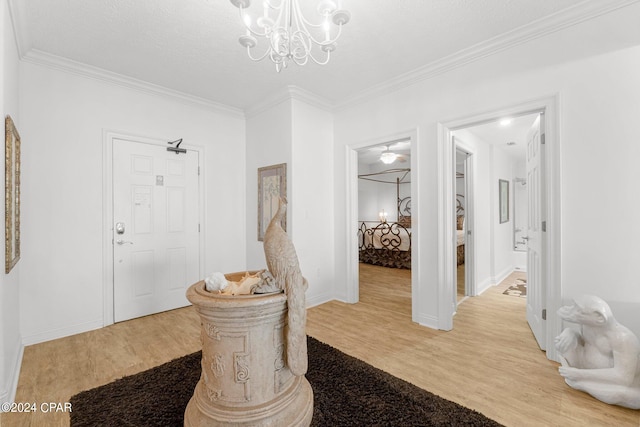 foyer entrance with an inviting chandelier, crown molding, and light wood-type flooring