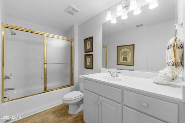 full bathroom with wood-type flooring, toilet, large vanity, and shower / bath combination with glass door