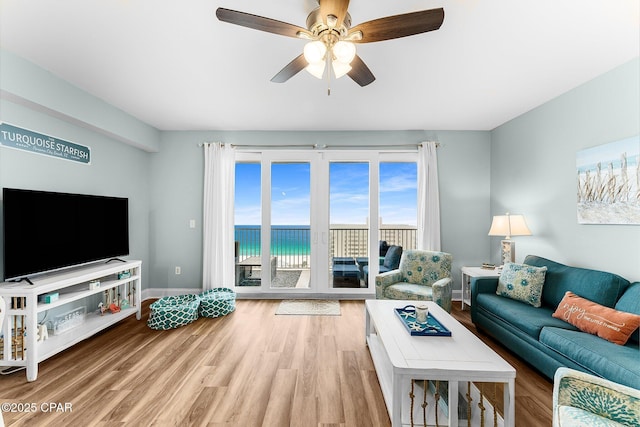 living room featuring a water view, ceiling fan, and light hardwood / wood-style floors