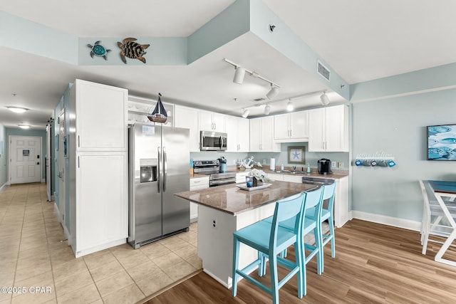 kitchen featuring a kitchen bar, white cabinetry, a center island, dark stone countertops, and stainless steel appliances