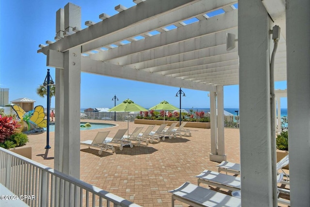 view of patio with a water view, a community pool, and a pergola