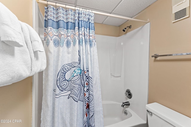 bathroom featuring a paneled ceiling, shower / bath combination with curtain, and toilet