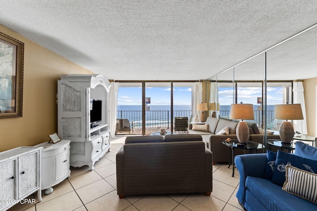 living room featuring expansive windows, light tile floors, a textured ceiling, and a water view