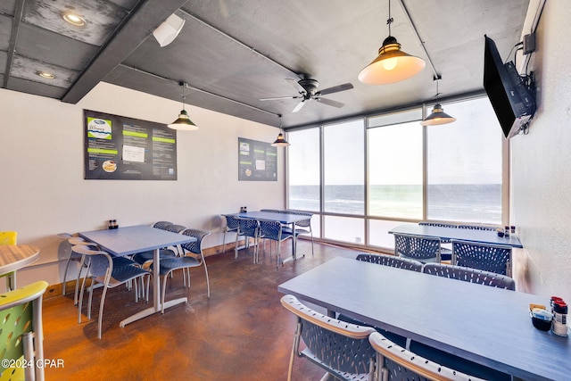 dining space featuring ceiling fan, expansive windows, and a water view