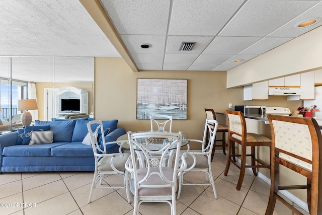 tiled dining area featuring a paneled ceiling