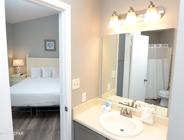 bathroom featuring toilet, hardwood / wood-style floors, curtained shower, and vanity