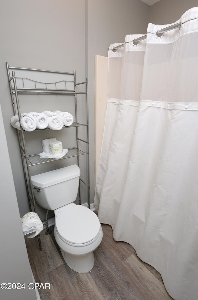 bathroom with toilet, hardwood / wood-style flooring, and curtained shower