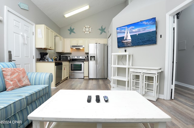 kitchen with high vaulted ceiling, appliances with stainless steel finishes, light hardwood / wood-style flooring, and cream cabinetry