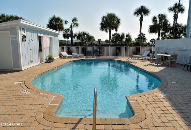 view of pool with a patio and an outbuilding