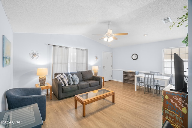 living room featuring lofted ceiling, light hardwood / wood-style flooring, ceiling fan, and a textured ceiling