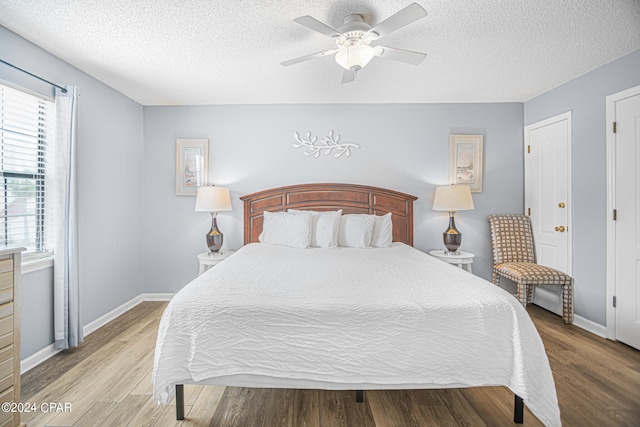 bedroom with a textured ceiling, ceiling fan, and hardwood / wood-style flooring