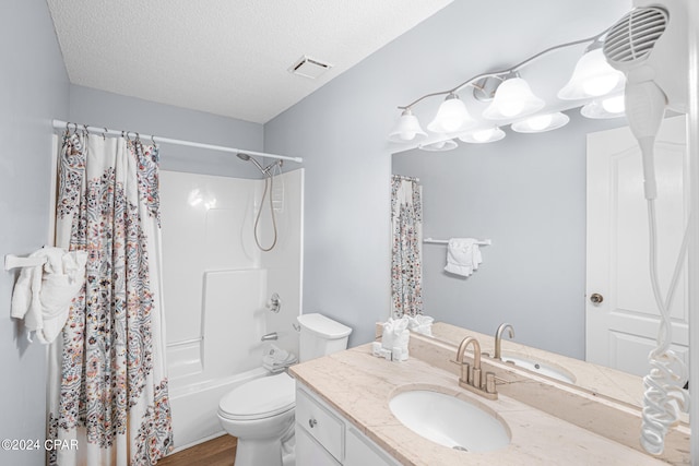 full bathroom with vanity, hardwood / wood-style floors, shower / tub combo with curtain, toilet, and a textured ceiling