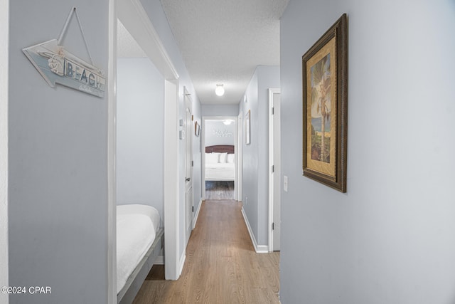 hallway with light hardwood / wood-style flooring and a textured ceiling