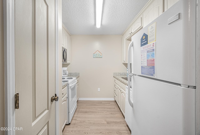 kitchen featuring light stone counters, a textured ceiling, white cabinets, white appliances, and light wood-type flooring