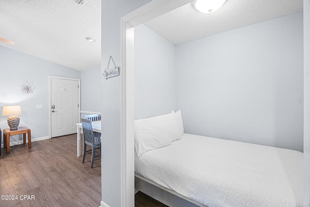 bedroom featuring dark hardwood / wood-style floors, a textured ceiling, and lofted ceiling