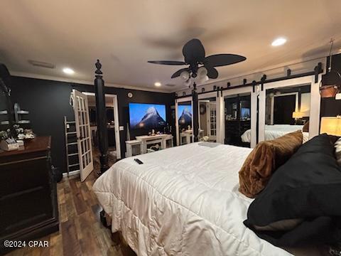 bedroom featuring access to exterior, hardwood / wood-style floors, a barn door, and ceiling fan