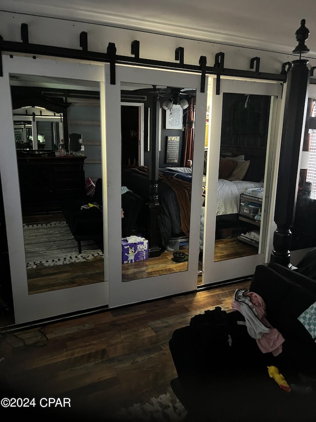 bedroom featuring dark wood-type flooring, access to outside, a barn door, and ceiling fan