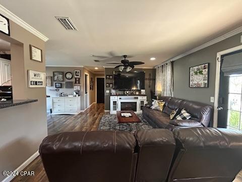 living room featuring wood-type flooring, crown molding, and ceiling fan