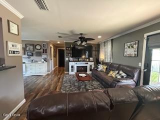 living room featuring dark wood-type flooring, crown molding, and ceiling fan