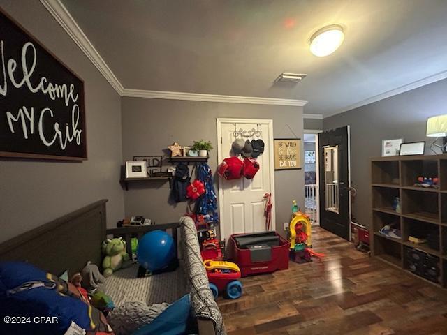 bedroom with hardwood / wood-style floors and ornamental molding