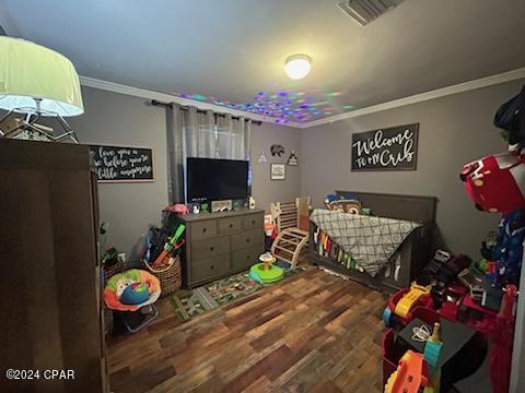 bedroom featuring wood-type flooring and crown molding