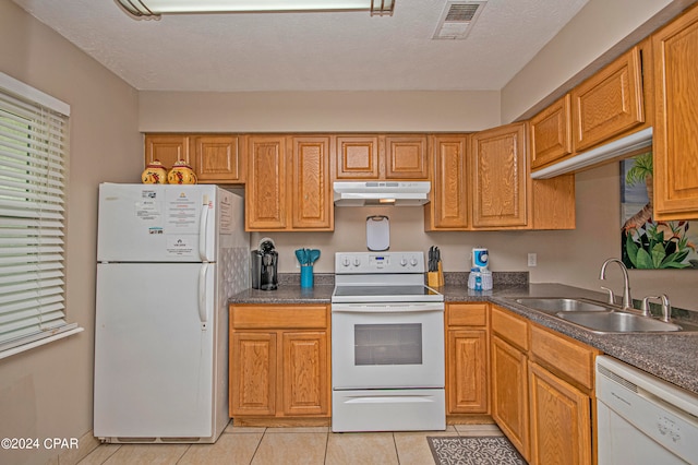 kitchen featuring sink, white appliances, light tile flooring, and a textured ceiling