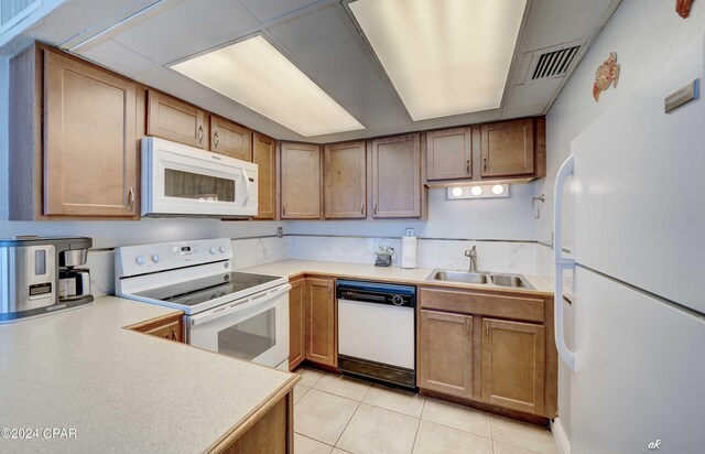 kitchen featuring white appliances, light tile patterned floors, and sink