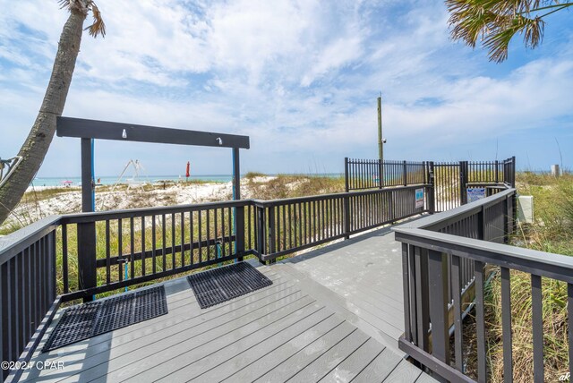 wooden deck with a water view and a view of the beach