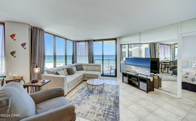 tiled living room featuring a wall of windows and a water view