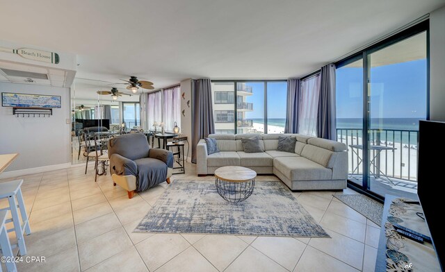 tiled living room with ceiling fan, a water view, expansive windows, and a wealth of natural light