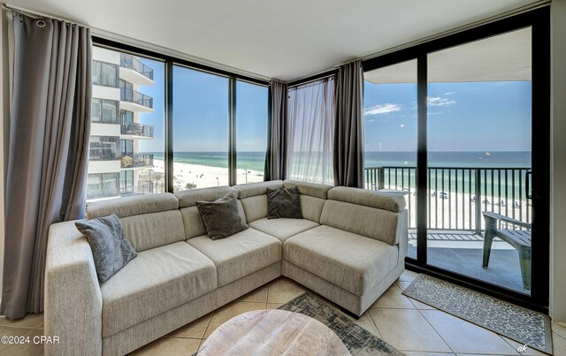 tiled living room with expansive windows, a view of the beach, and a water view