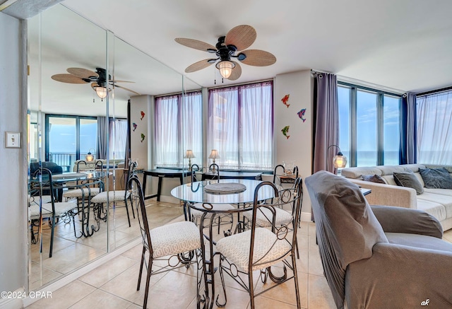 tiled dining area with plenty of natural light, ceiling fan, and a water view