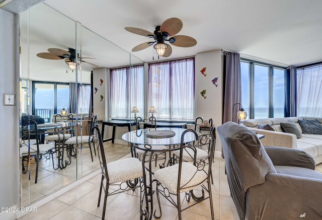 dining area featuring a water view, light tile patterned floors, and ceiling fan