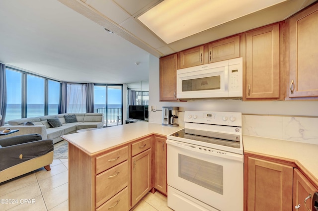 kitchen featuring a water view, white appliances, kitchen peninsula, and light tile patterned floors