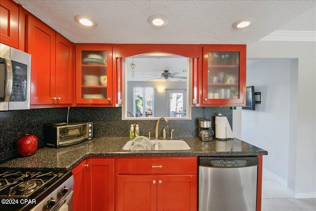 kitchen with ceiling fan, sink, backsplash, appliances with stainless steel finishes, and dark stone counters