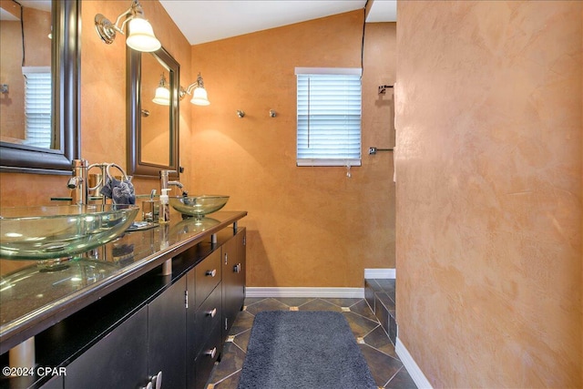 bathroom with tile patterned flooring, vaulted ceiling, and vanity