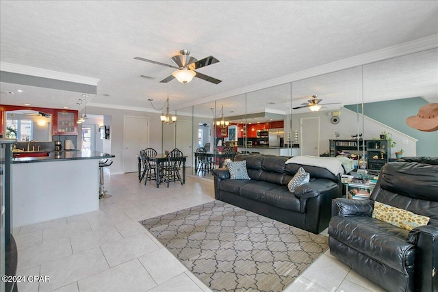 living room with ceiling fan with notable chandelier, light tile patterned floors, ornamental molding, and a textured ceiling