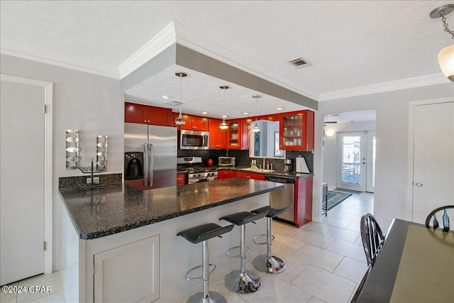 kitchen featuring appliances with stainless steel finishes, pendant lighting, light tile patterned flooring, and a textured ceiling